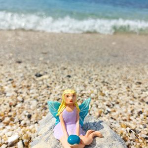 Handmade polymer clay fairy miniature holding a blue magic rock