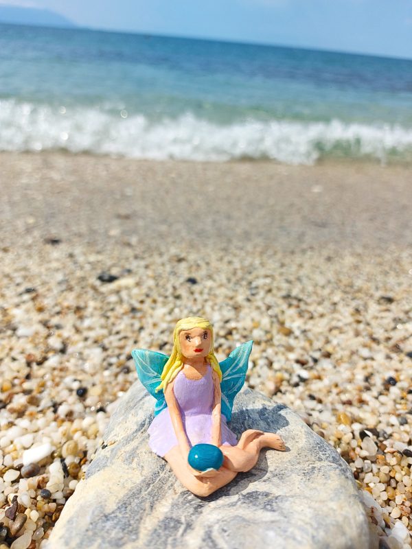 Handmade polymer clay fairy miniature holding a blue magic rock