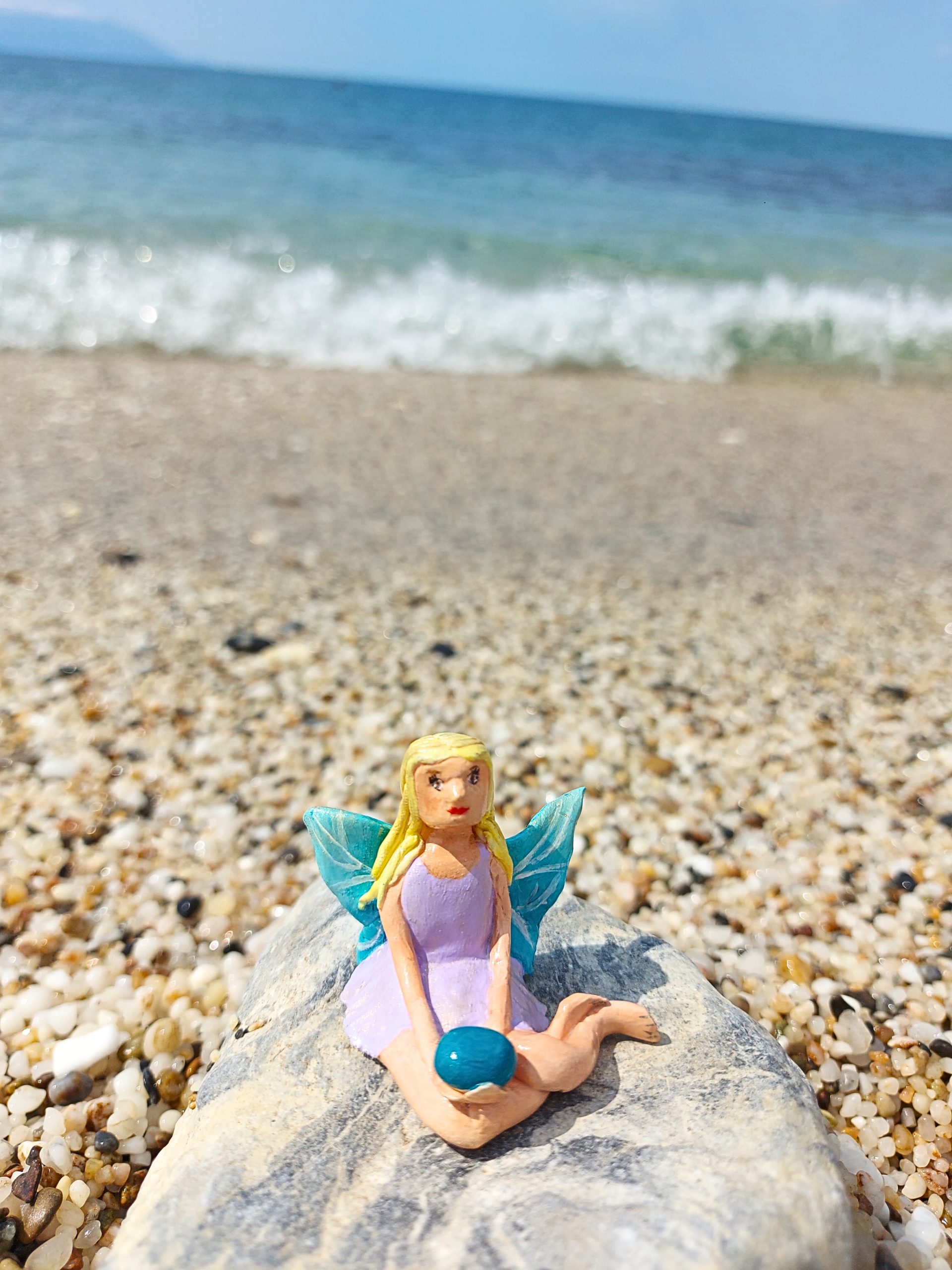 Handmade polymer clay fairy miniature holding a blue magic rock