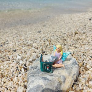 Handmade fairy miniature displayed with other clay miniatures in a whimsical setting